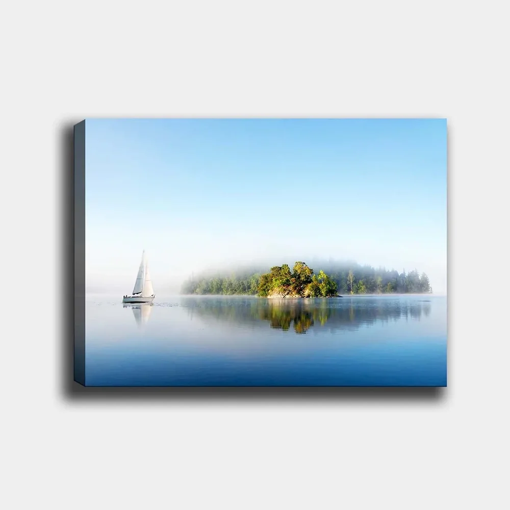 Lerretsbilde 70x100 cm - Seilbåt glir over en speilblank innsjø med en tåkete øy i bakgrunnen v:8836217